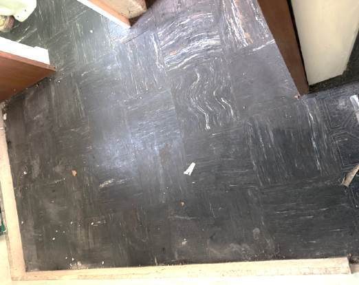 Older resilient floor tiles photographed during a building survey; appearance alone cannot confirm their composition